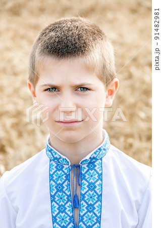 Portrait of child in traditional embroidered Ukrainian shirt on background of wheat field on sunny day. Blue embroidery. Boy's face is sad. Independence Day and the Constitution of Ukraine Portrait of child in traditional embroidered Ukrainian shirt on background of wheat field on sunny day. Blue embroidery. Boy's face is sad. Independence Day and the Constitution of Ukraine 91482981