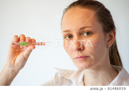 Woman being sick having flu looking at temperature on thermometer. Woman being sick having flu looking at temperature on thermometer. 91486059
