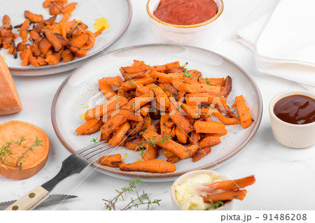 Sweet potato fries in a bowl with mayo sauce, homemade roasted pumpkin in the oven, close up 91486208