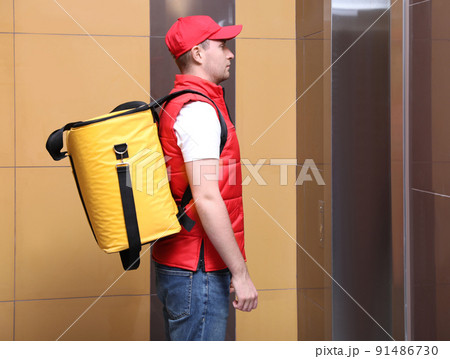 Male courier with thermo bag waiting for elevator. Food delivery service Male courier with thermo bag waiting for elevator. Food delivery service 91486730