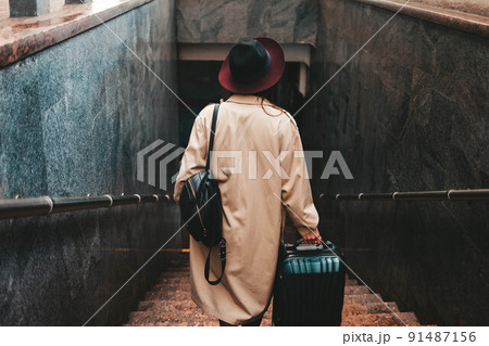 Stylish woman with a suitcase get down the stairs of the train station Stylish woman with a suitcase get down the stairs of the train station 91487156