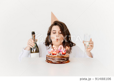a happy woman with champagne and a birthday cake with candles. a happy woman with champagne and a birthday cake with candles. 91488106