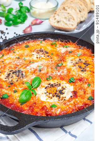 Shakshuka with eggs, Italian sausage, tomato sauce, in cast iron pan, vertical Shakshuka with eggs, Italian sausage, tomato sauce, in cast iron pan, vertical 91489101