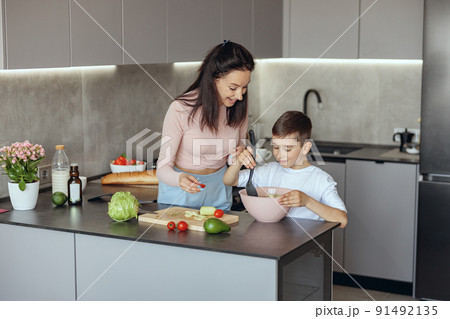 Happy Caucasian mother teaching small son to cook vegetables salat at home. Happy Caucasian mother teaching small son to cook vegetables salat at home. 91492135