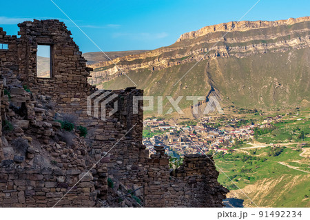 walls of abandoned houses on a mountain cliff in the ghost village of Gamsutl in Dagestan, on the opposite side of the valley the inhabited village of Chokh is visible 91492234