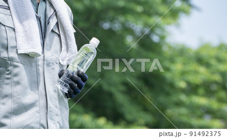 ペットボトルの水を持つ作業服の男性|建設業の熱中症対策イメージ ペットボトルの水を持つ作業服の男性|建設業の熱中症対策イメージ 91492375