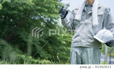 ペットボトルの水を飲む作業服の男性｜建設業の熱中症対策イメージ 91492633