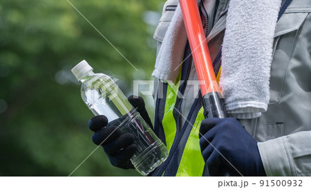 ペットボトルの水を持つ警備員の男性｜建設業・警備業の熱中症対策イメージ 91500932