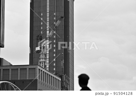 モノクローム　高層ビルと工事用クレーンの動くシーン　人の頭添え　 91504128