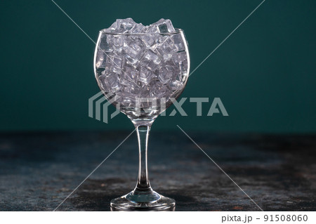 Glass full of ice standing on a table in the dark Glass full of ice standing on a table in the dark 91508060
