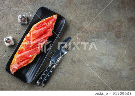 Traditional Spanish breakfast. Tostada with different toppings on a dark background. Top view with copy space 91509633