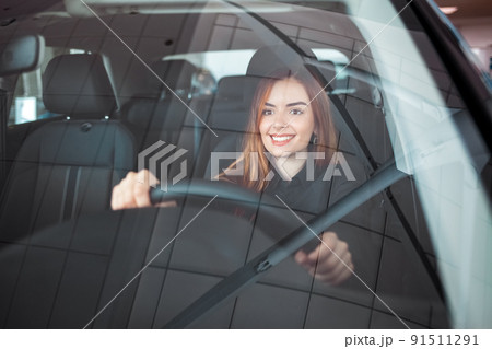 Smiling woman sitting at a car in a showroom. Smiling woman sitting at a car in a showroom. 91511291