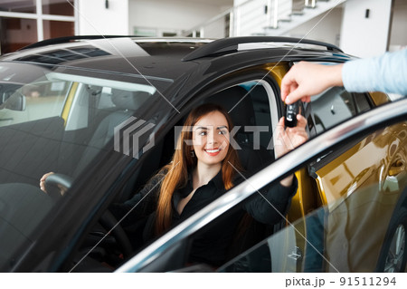 Car dealership seller gives client a car key. 91511294