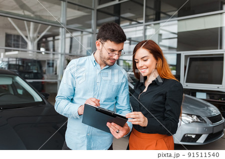 Car showroom seller gives papers to a client. 91511540