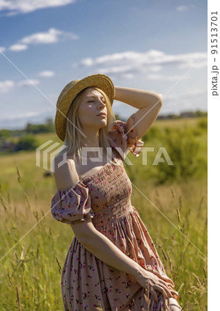 Happy beautiful girl, holding her hand on her hat, admires the beauty in the meadow at sunset. Happy beautiful girl, holding her hand on her hat, admires the beauty in the meadow at sunset. 91513701