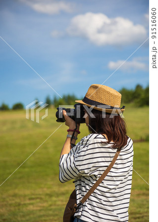 晴れた高原でカメラを構える女性 91516060