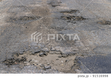 poor paved road with a lot of holes and potholes 91516998