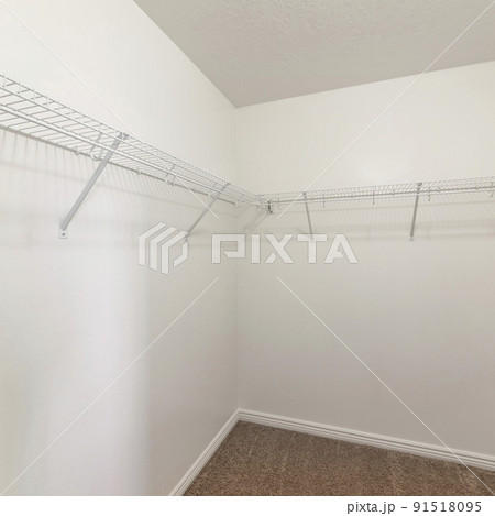 Square frame Empty storage room with wall mounted white metal shelves and hooks 91518095