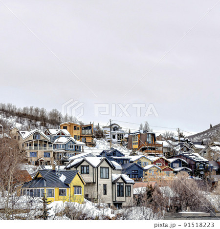 Square Mountain town on a cloudy winter landscape with homes on snowy slope terrain 91518223