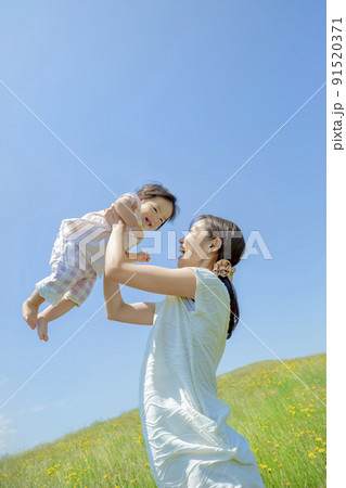 野花の咲く丘で遊ぶ母と娘 91520371