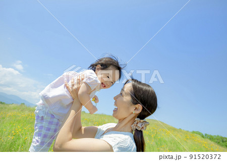 野花の咲く丘で遊ぶ母と娘 91520372
