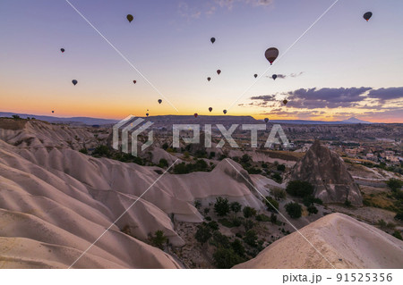 Hot air balloons flying over a volcanic landscape at Cappadocia, Turkey 91525356