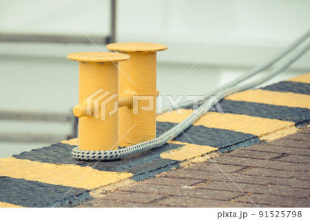 Thick rope and yellow bollards on wharf using for anchorage of yachts Thick rope and yellow bollards on wharf using for anchorage of yachts 91525798