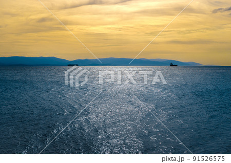seascape with dark blue sea and yellow sunset sky. Colorful sunset and cloudy sky over dark islands against dark blue sea. 91526575