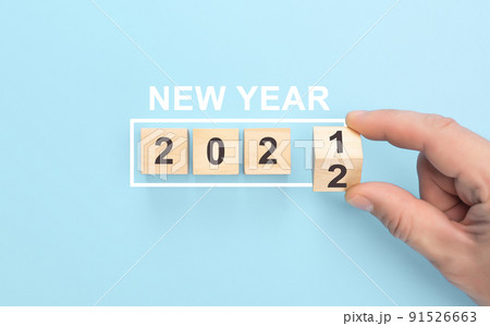 New year 2021 change to 2022 concept. Hand flip over wood cube block. Flipping wooden cubes with the Year number 2021 and 2022, New Year concept. blue background New year 2021 change to 2022 concept. Hand flip over wood cube block. Flipping wooden cubes with the Year number 2021 and 2022, New Year concept. blue background 91526663