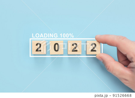 Business concept of planning 2022. Loading new year 2022 with hand putting wood cube in progress bar. blue background. poster, banner Business concept of planning 2022. Loading new year 2022 with hand putting wood cube in progress bar. blue background. poster, banner 91526668