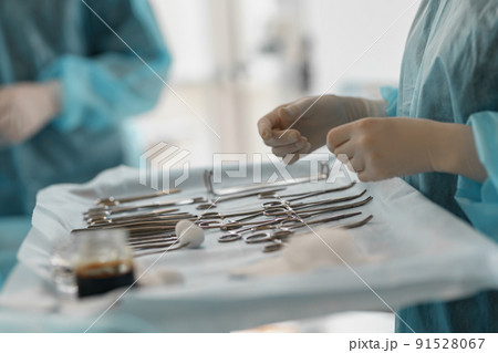Surgical instruments and tools including scalpels forceps and tweezers arranged on table for surgery 91528067