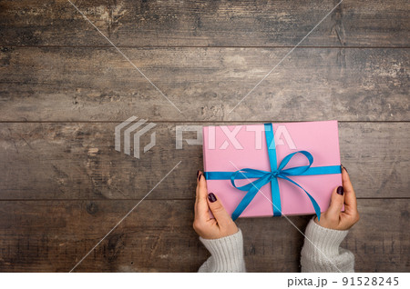 Valentine's Day composition with women's hands holding pink gift box on white background. Flat lay, top view holiday concept. 91528245