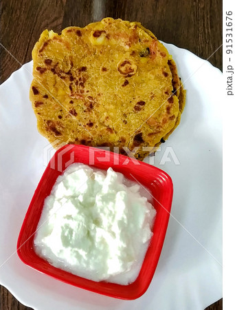 Indian breakfast dish.Stuffed potato paratha or channa dal paratha served with curd. Selective focus 91531676