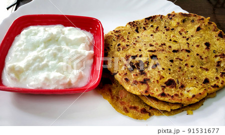 Indian breakfast dish.Stuffed potato paratha or channa dal paratha served with curd. Selective focus 91531677
