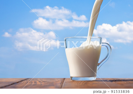 milk pouring into glass cup on table milk pouring into glass cup on table 91533836