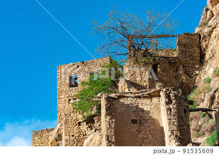 ruins of stone houses attached to the rock in the depopulated village of Gamsutl in Dagestan 91535609