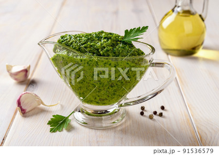 Green sauce in a gravy boat on a table. Chimichurri dipping sauce from fresh parsley. Green sauce in a gravy boat on a table. Chimichurri dipping sauce from fresh parsley. 91536579