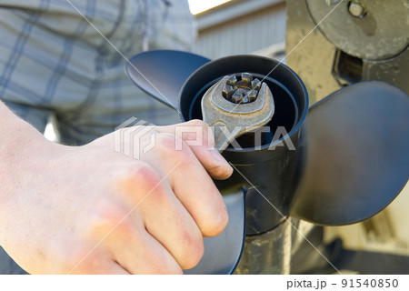 man changing propeller on outboard motor. Repairing outboard motor for boat, replacing screw. 91540850