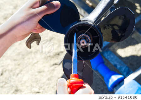 man changing propeller on outboard motor. Repairing outboard motor for boat, replacing screw. 91541080