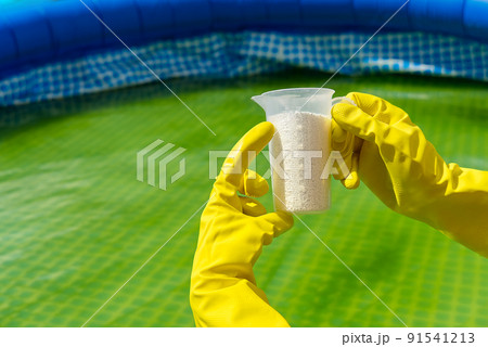 addition of chlorine powder for the pool to remove algae and disinfect water. inflatable swimming pool care concept. addition of chlorine powder for the pool to remove algae and disinfect water. inflatable swimming pool care concept. 91541213