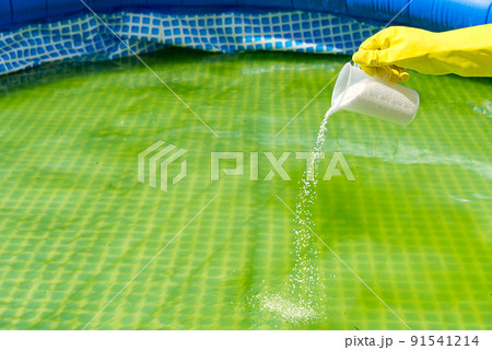 addition of chlorine powder for the pool to remove algae and disinfect water. inflatable swimming pool care concept. addition of chlorine powder for the pool to remove algae and disinfect water. inflatable swimming pool care concept. 91541214