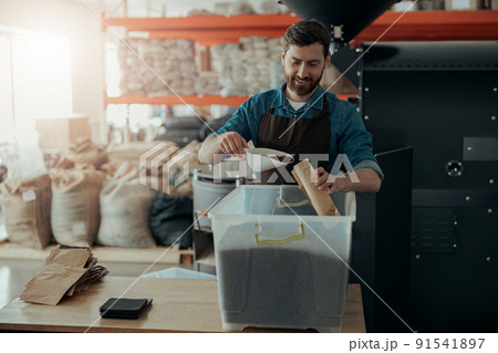 Business owner packs roasted coffee beans into packages for sale Business owner packs roasted coffee beans into packages for sale 91541897