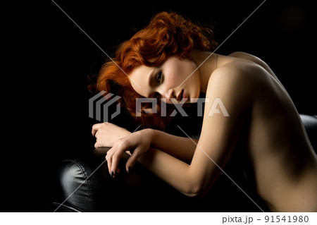 Alluring topless red haired woman on black couch Alluring topless red haired woman on black couch 91541980