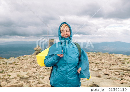 50s woman hiking with Ukraine flag at mountains with sports backpack. Travel adventure concept.  91542159