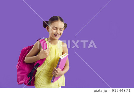 Cheerful preteen schoolgirl with backpack and notebooks laughing on purple background. Cheerful preteen schoolgirl with backpack and notebooks laughing on purple background. 91544371