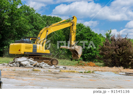 An excavator chops and crumbles old concrete crusher for concrete slabs on construction site 91545136