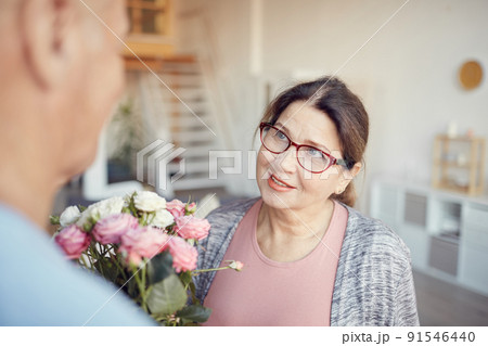 Smiling charming senior lady in eyeglasses receiving tender bouquet from husband on Valentines day 91546440