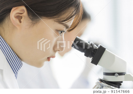 顕微鏡を覗く白衣の女性 研究 実験 91547666