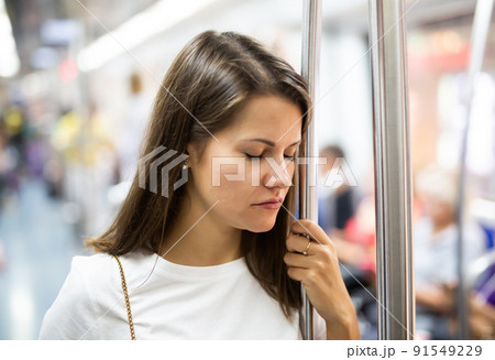 Tired woman standing in subway car Tired woman standing in subway car 91549229