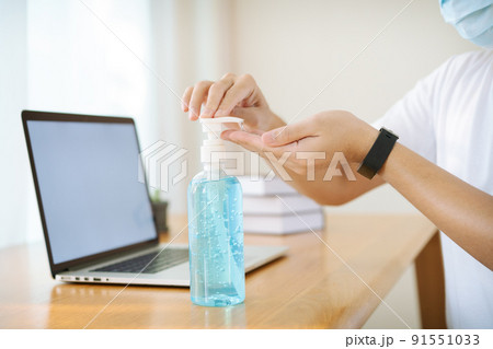 Unrecognizable Asian man with protective face mask using alcohol gel to wash or clean up his hands and to protect from virus pandemic. Hygienic awareness lifestyle concept. Man using an alcohol gel. 91551033